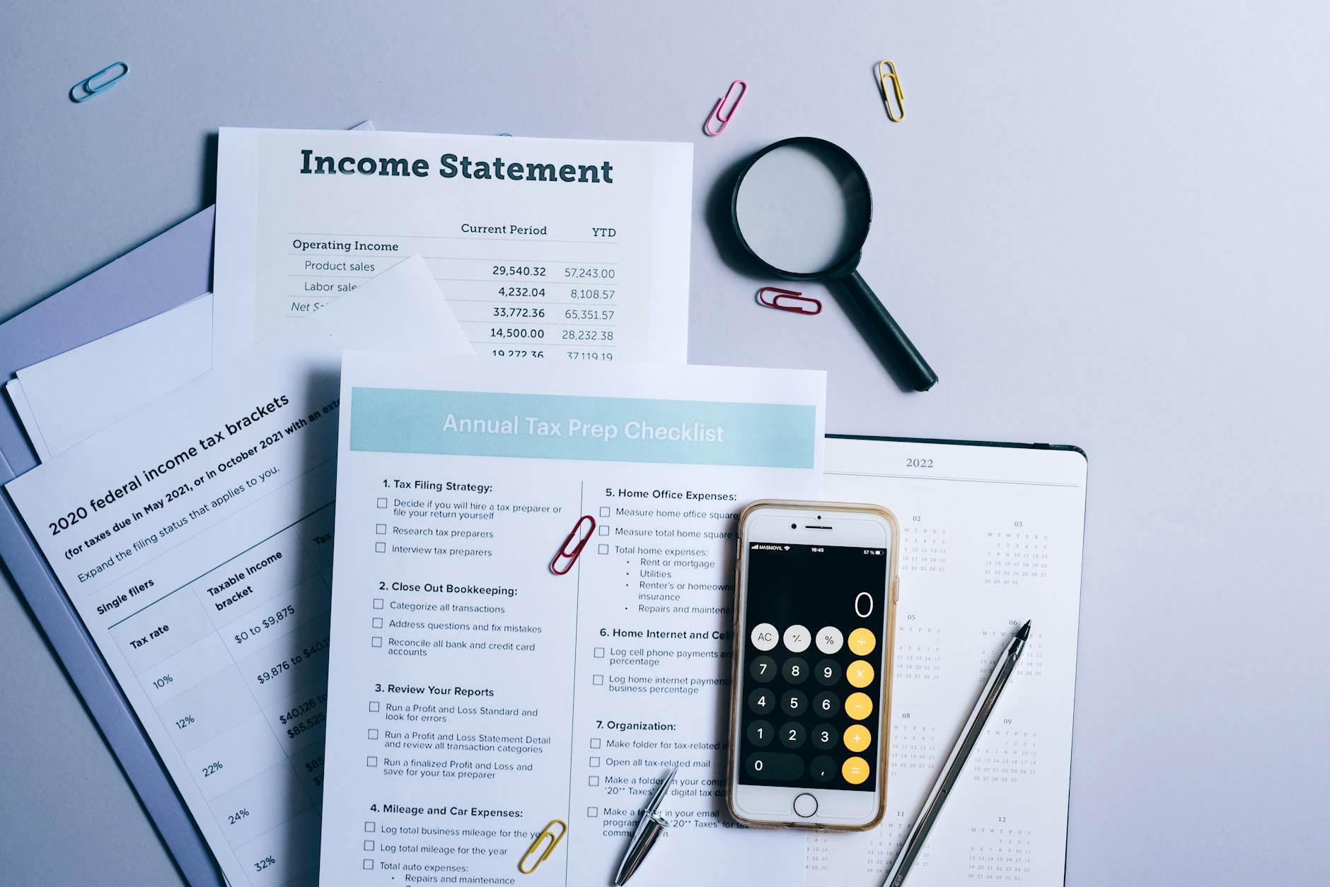 a mobile phone and documents near the magnifying glass on the table